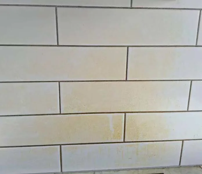 Cooktop area before cleaning with grease marks on the white splashback and tile joints